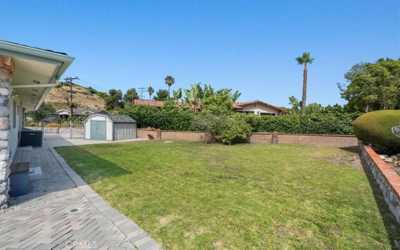 Outdoor pavers leading into vast open grass area, plus outdoor shed.