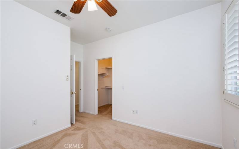 The guest bedroom has plantation shutters, a ceiling fan and walk-in closet.