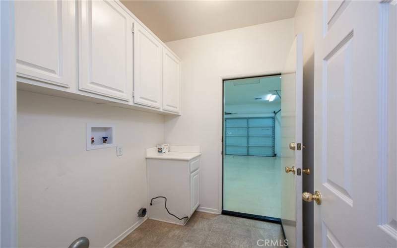 Laundry room with plenty of cabinets leading tom the finished 2-car garage with epoxy floors and newer water heater.