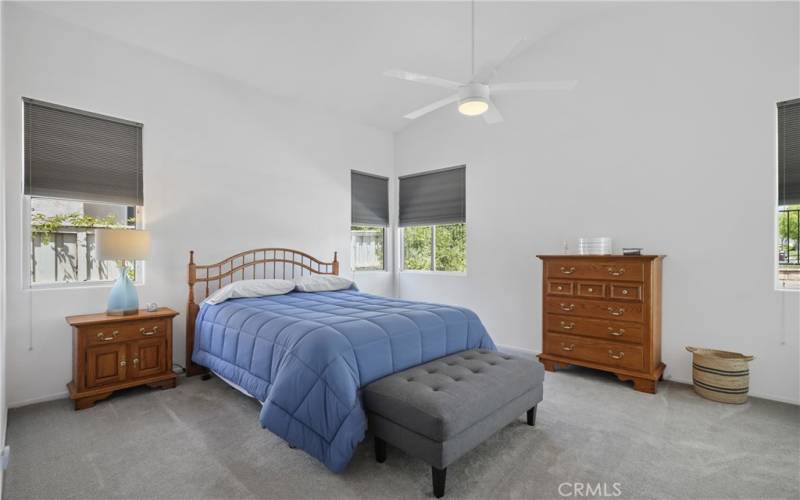 Primary bedroom is downstairs with a  ceiling fan soft shades  and shutters on the sliding door.