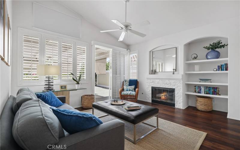 Your family room with a stacked stone fireplace, built-in shelving and shutters.