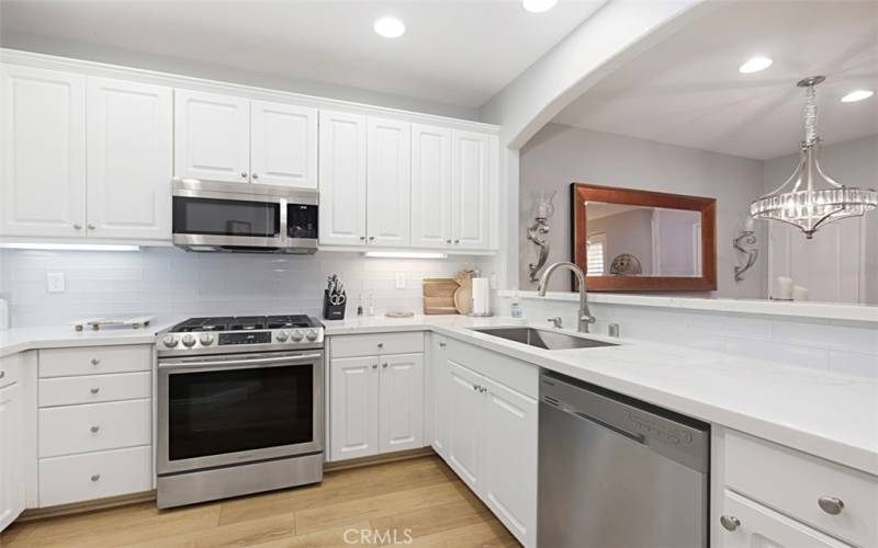 Upgraded kitchen with quartz countertops, glass tile backsplash, stainless steel appliances and sink.