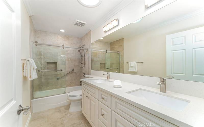 Primary bathroom with quatrz countertops and new cabinetry, low step in shower