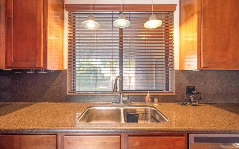 Kitchen sink window looks out over the patio to the big tree and yard.