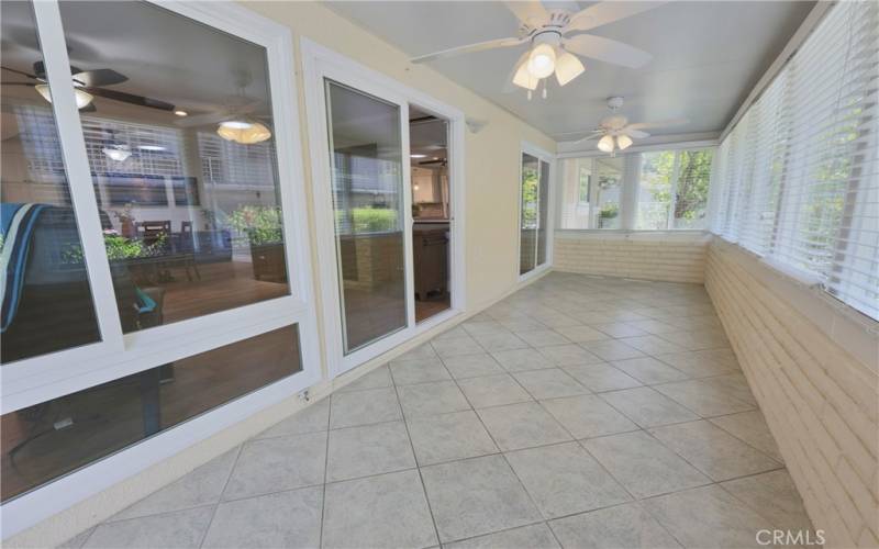 Great enclosed sunroom with ceiling fans, dual pane windows, tile floor and custiom blinds