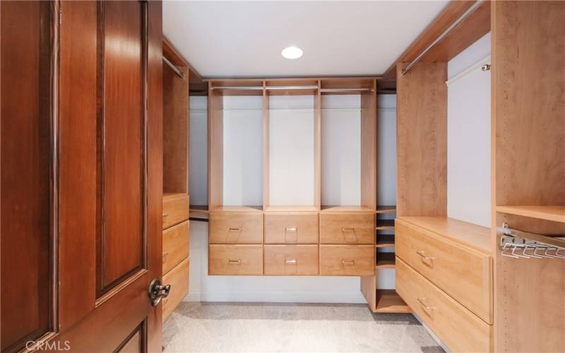 Primary walk in closet complete with custom cabinetry offering plenty of hanging and drawer space