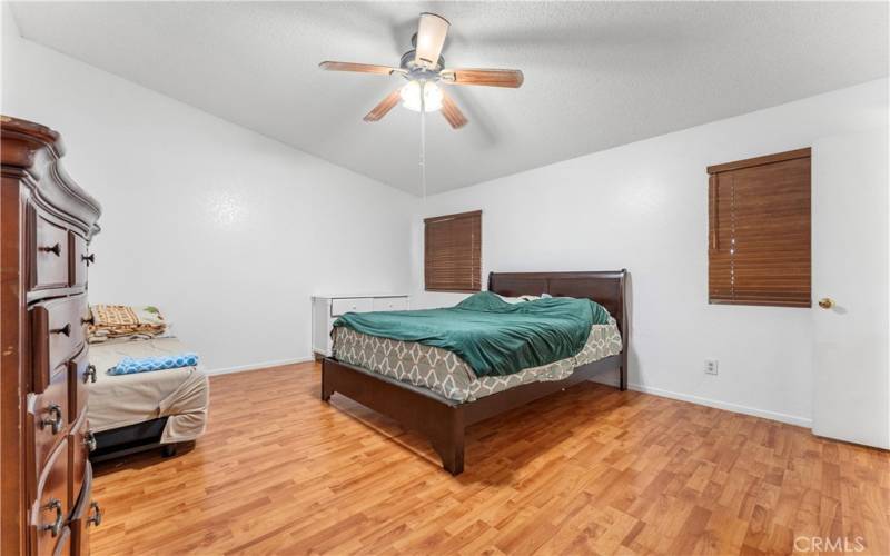 Primary bedroom with ceiling fan. Windows face the backyard.