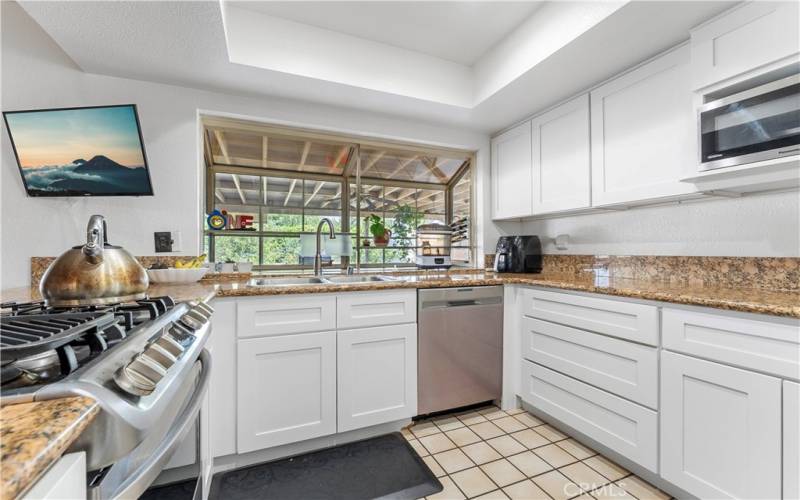 Shaker cabinets and granite counters with a large garden window overlooking the backyard.