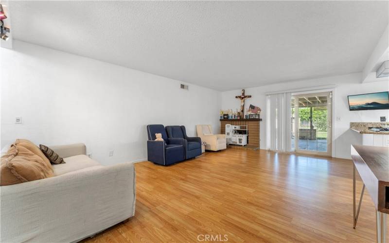 Ample space in the family room with laminate flooring and fireplace in the corner. Sliders to the large covered patio and pool. Wrap around from family room to the kitchen.