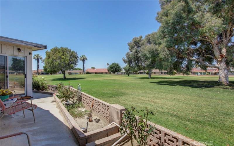 View of serene golf course from back patio with slider into dining room.