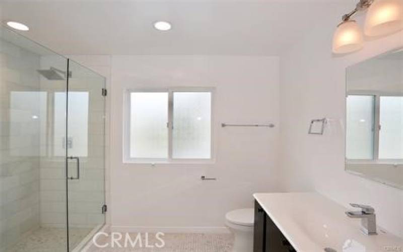 Clean modern bathroom with walk-in shower and storage space