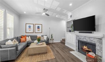 Living room features luxury vinyl flooring, recessed lighting, remote operated ceiling fan, gas-operable fireplace, mounted smart TV with built in Bose soundbar, & privacy plantation shutters