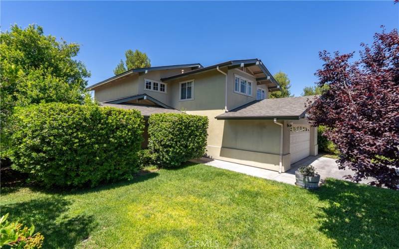 The front side yard boasts a lush, mature landscape.