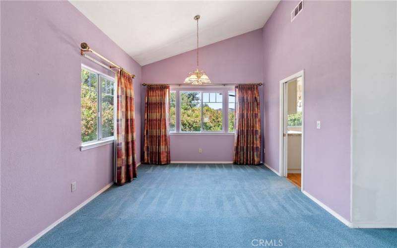 From the living room, enter to the dining area. With the same openness, this room also has high vaulted ceilings, carpeting and chandelier.