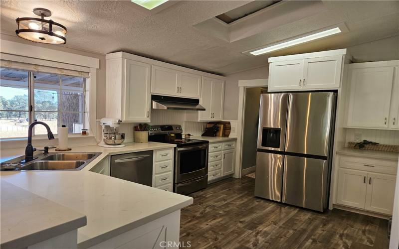 Main home kitchen boasts granite and stainless steel appliances as well as laminate flooring.