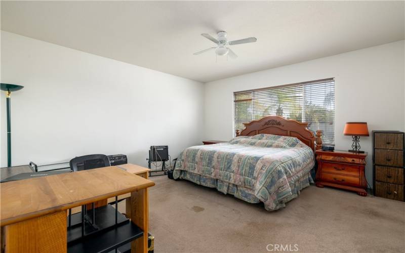 Master bedroom with window blinds and ceiling fan.