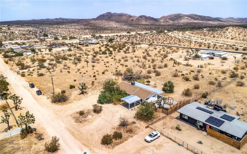 Arial view of front of home and unpaved road leading to home.