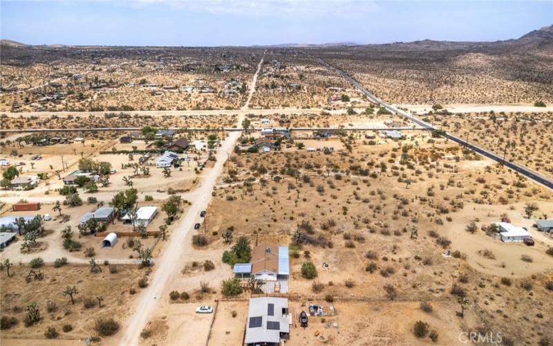 Arial view of front of home and unpaved road leading to home.