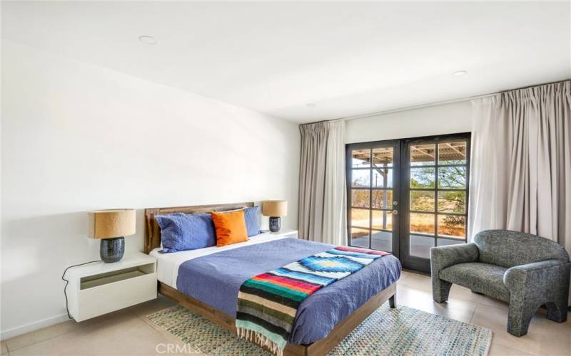 Primary bedroom towards back patio, including dual pane French doors and floating nightstands.