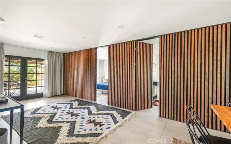 Living room area with fluted panels hidden room doors open.