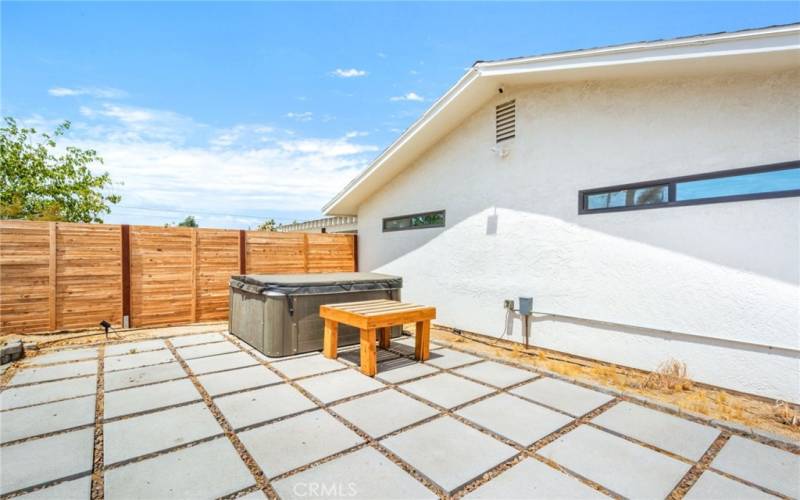 Side yard above ground heated spa and horizontal wooden fence for privacy.