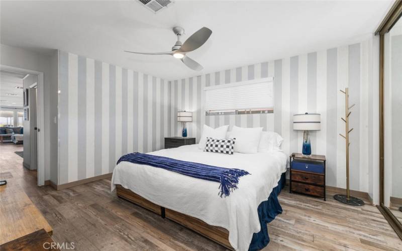 Master bedroom with nicely appointed wall covering and ceiling fan with remote control feature.