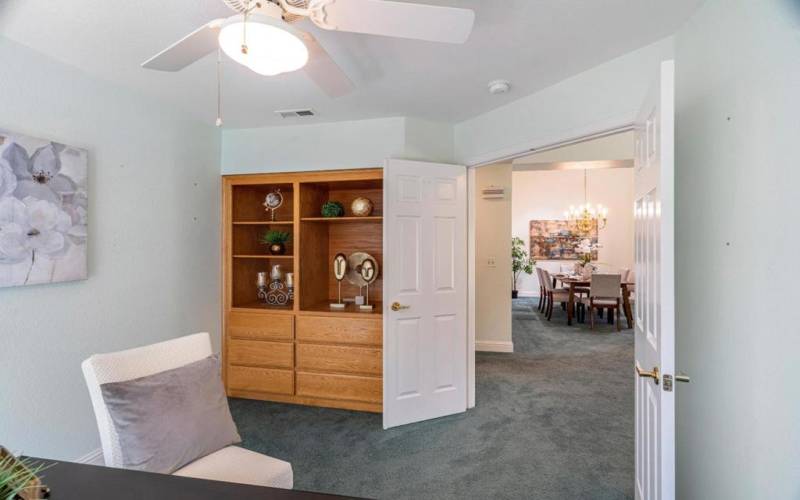 Double doors, ceiling fan along with extra flushed cabinet storing in the study room.