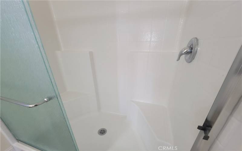 The master walk-in shower complements the two sinks with his 'n' her in-shower built-in seating.