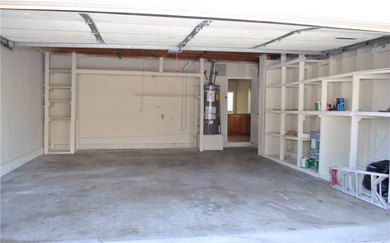 Two car garage with storage shelves and direct access.