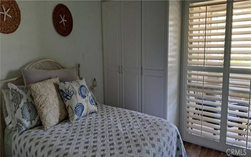 cozy bedroom with extra storage closet and plantation shutters