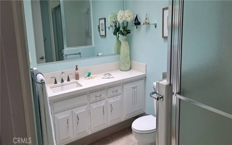 bathroom has corian counters and a cut down shower