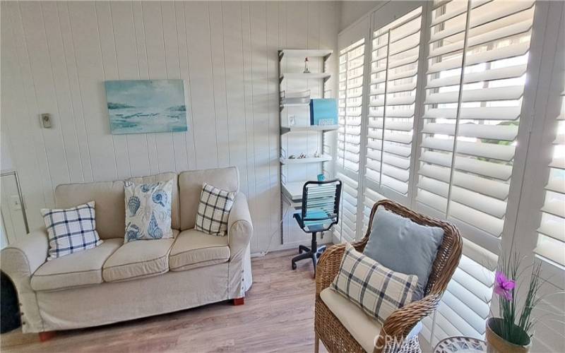 living area showing built in desk and plantation shutters