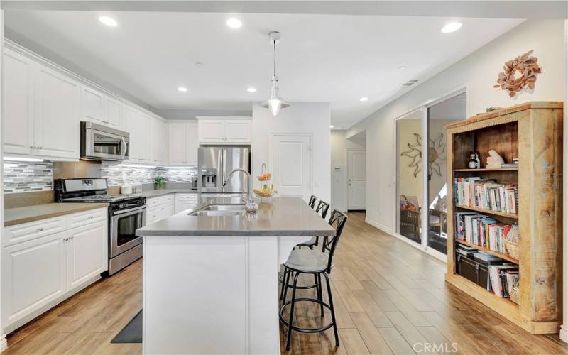 Spacious kitchen area w/ stainless steel appliances, quartz countertops, island breakfast bar, custom cabinetry and nautical pendant light