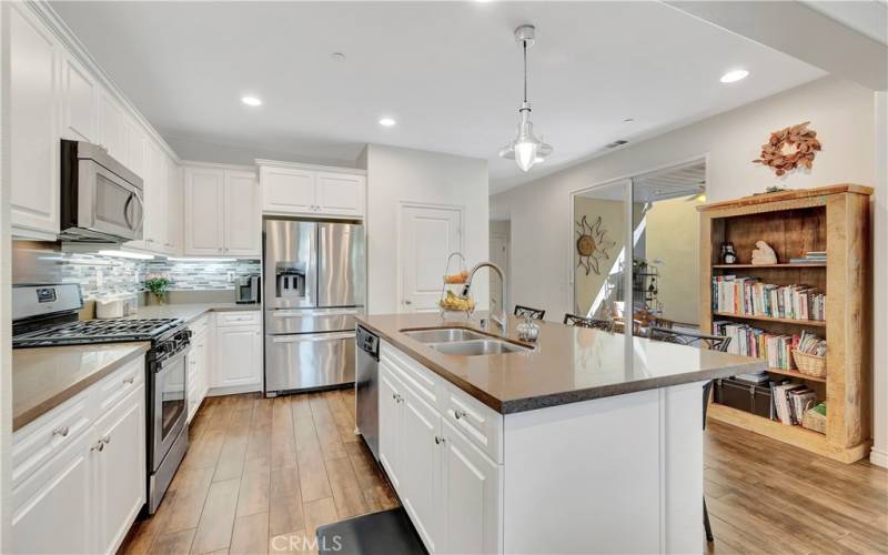  Spacious kitchen w/ stainless steel appliances, quartz countertops, island breakfast bar, custom cabinetry and nautical pendant light