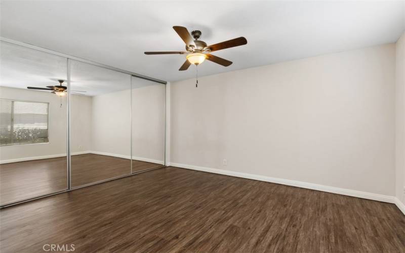 Primary bedroom with ceiling fan, and mirrored closet doors