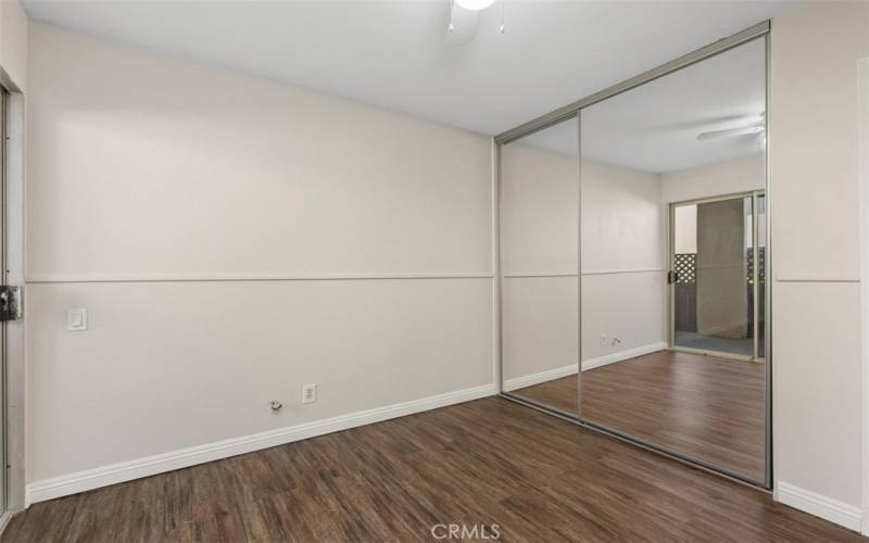 Secondary bedroom with a ceiling fan, mirrored closet doors,  and laminate flooring