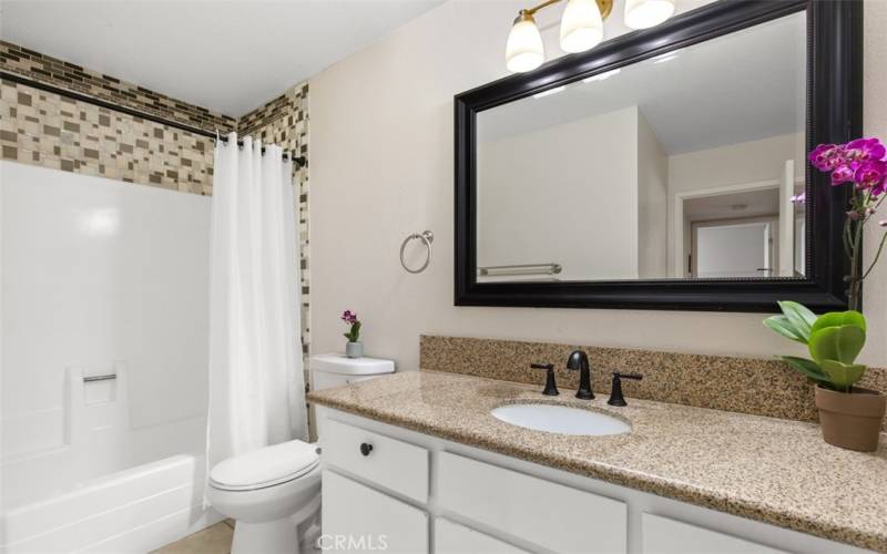 Bathroom with granite counter top and newer cabinet, faucet, mirror, toilet, and shower