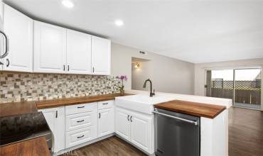 Remodeled kitchen with upgrades,  you can see the Farm house sink, cabinets, butcher block counter, backsplash, newer faucet, Viking dishwasher, New Stove, and a microwave.