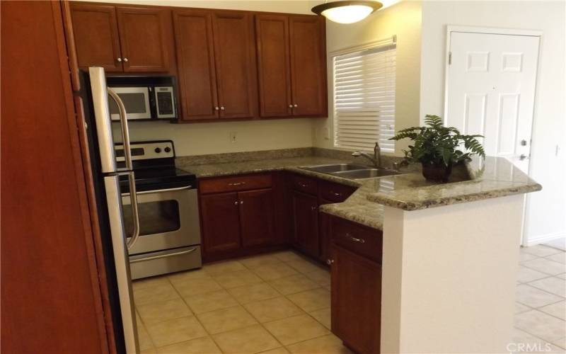 The kitchen has lots of cabinets, stainless stove, microwave, dishwasher and refrigerator.