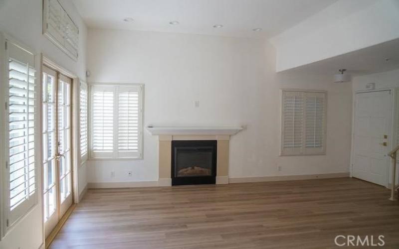 Spacious living room with new flooring, paint, and an electric fireplace feature.