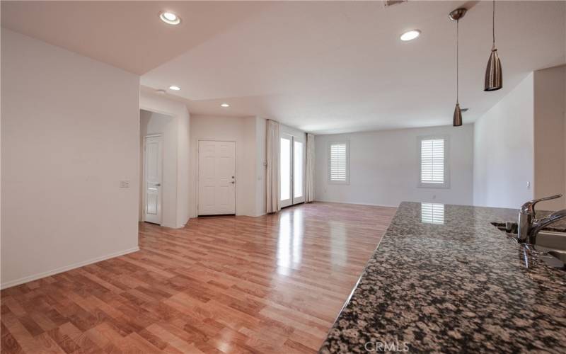 Kitchen island with breakfast bar and stainless steel sink, dining room of left, entry and living room on right.
