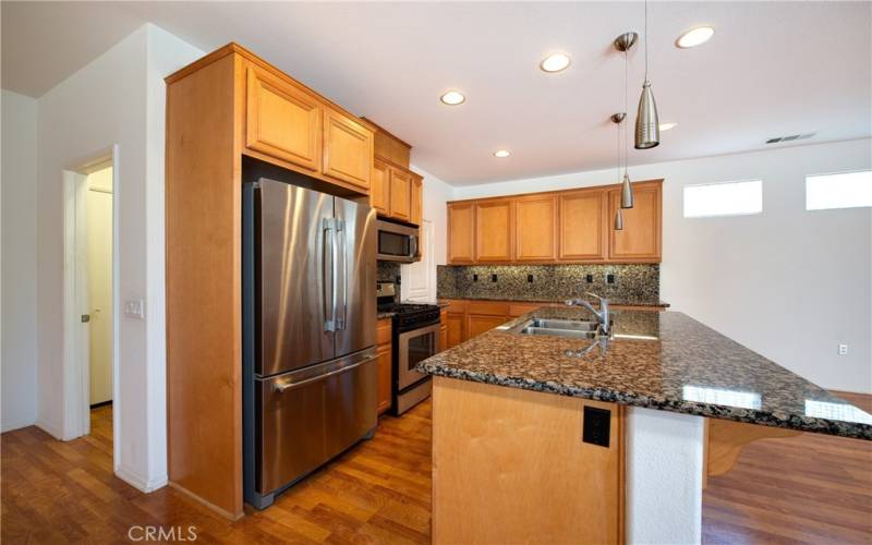 The gourmet kitchen features stainless steel appliances, inland with sink, breakfast bar and pendant lights, granite type counters and full backsplashes.