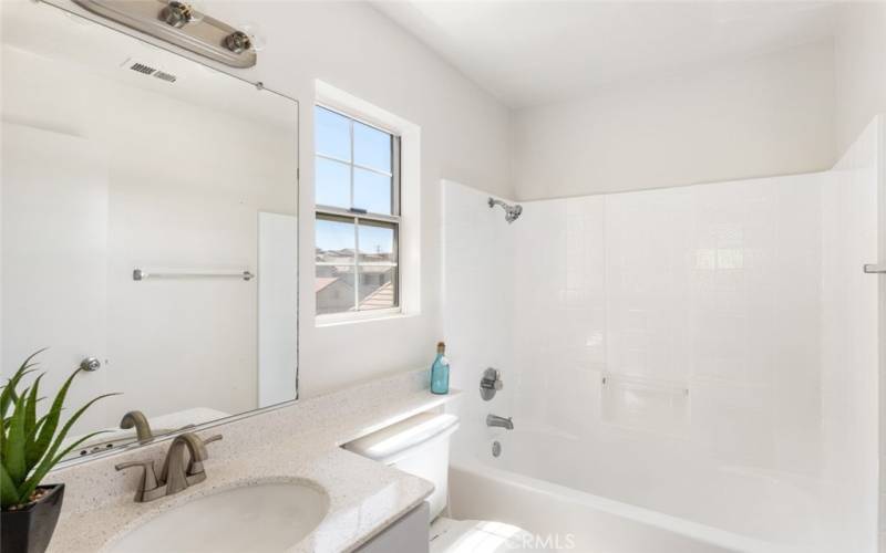 Clean, white bathroom with a large mirror and window