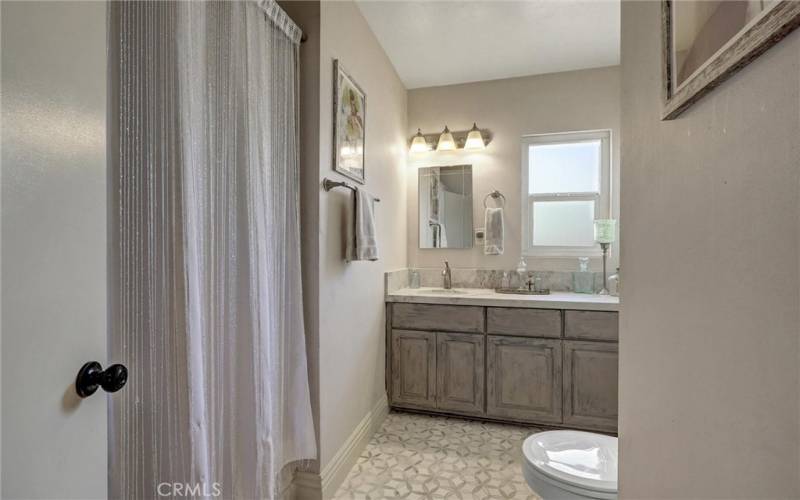 Hall full bathroom with Quartzite countertop and tub walls