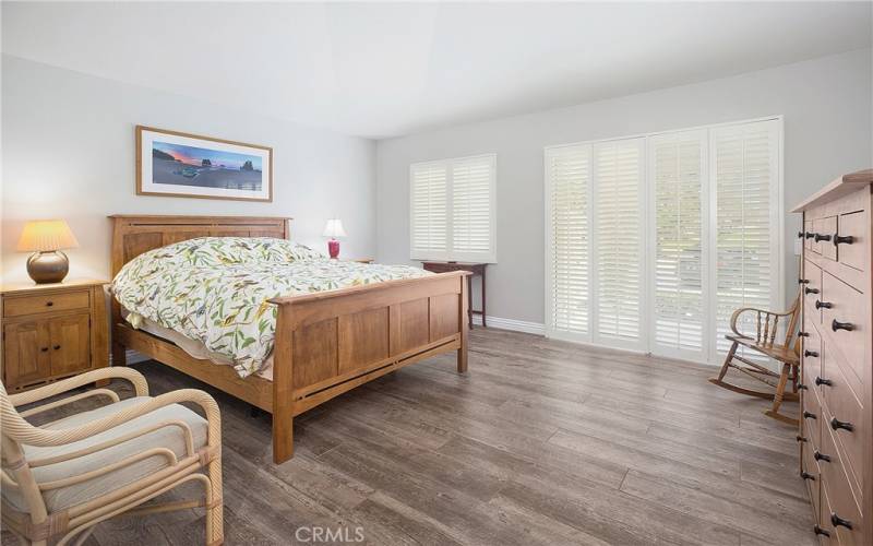 Primary bedroom sliding doors that lead to green belt and patio