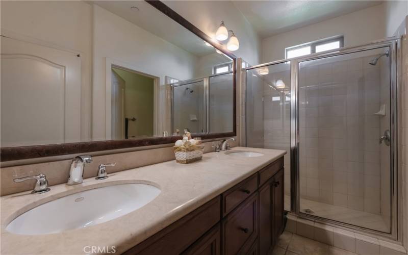 Primary bathroom with dual sinks and glass enclosed shower