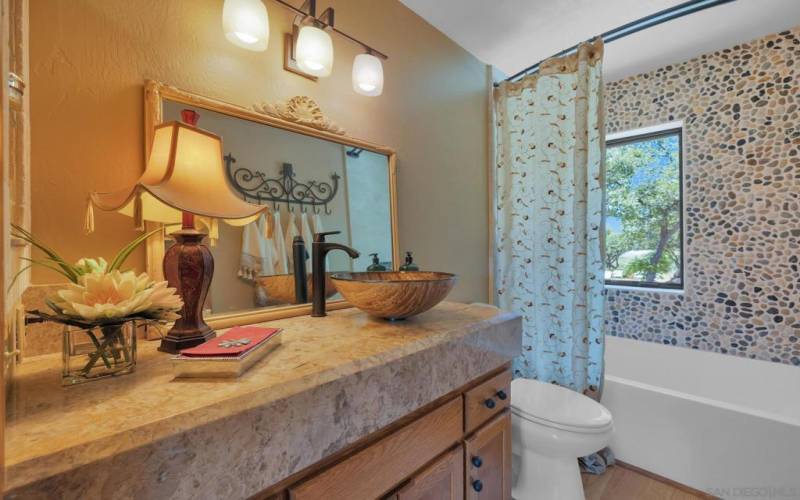 The custom granite counters, river rock and stone bath wall are extra high and elegantly designed.