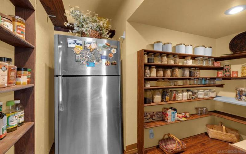 This cook's pantry is full of shelves for storage and features a second full-sized refrigerator.