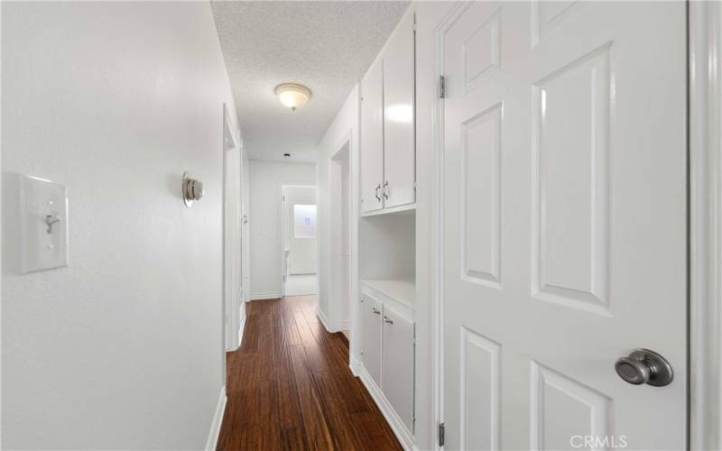 Walk down the Hallway bamboo floor to guest closet and linen storage plus thermostat for Heat & A/C control and access to bedrooms & baths