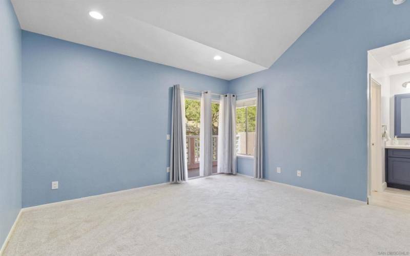 Primary bedroom with vaulted ceilings and sliding doors to your private balcony